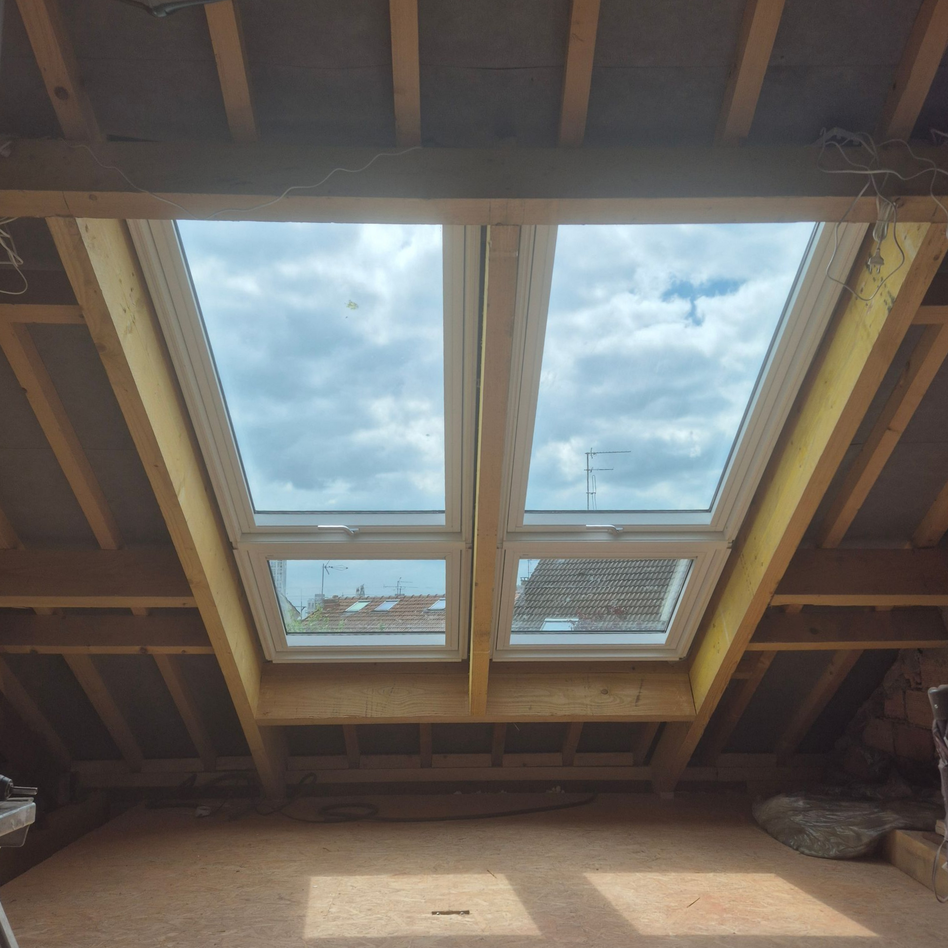 Bureau mansardé lumineux avec puits de lumière, bureau, tapis et deux chaises blanches.