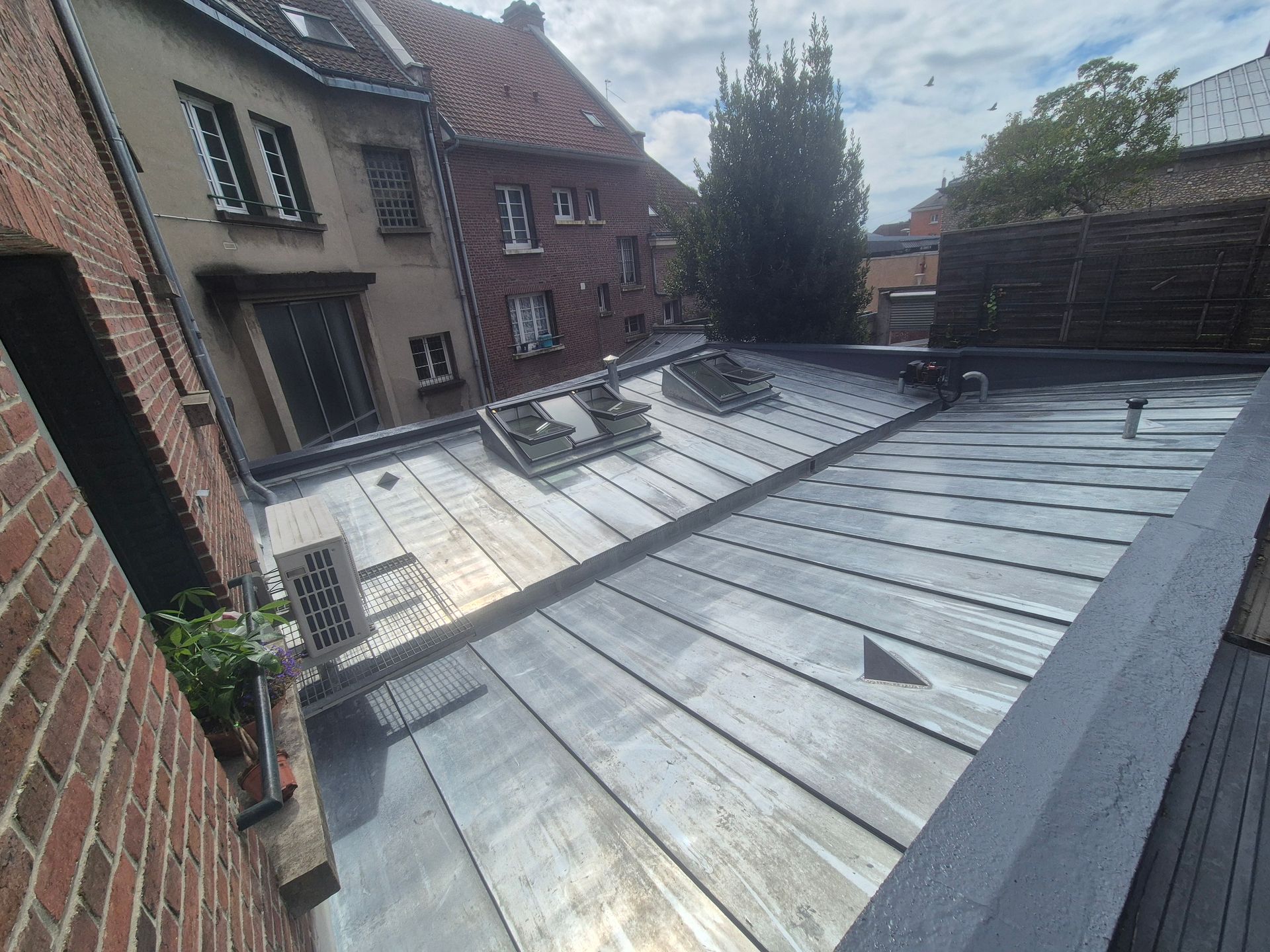 Solin métallique autour d'une cheminée sur un toit en tuiles en terre cuite.