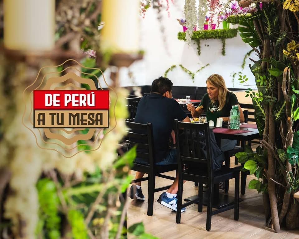 Personas cenando en una mesa de restaurante; decoración de exuberante vegetación; logo 