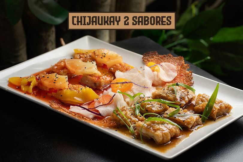 Chijaukay con dos sabores: Trozos de pollo en salsa, servidos con rodajas de fruta en un plato blanco.