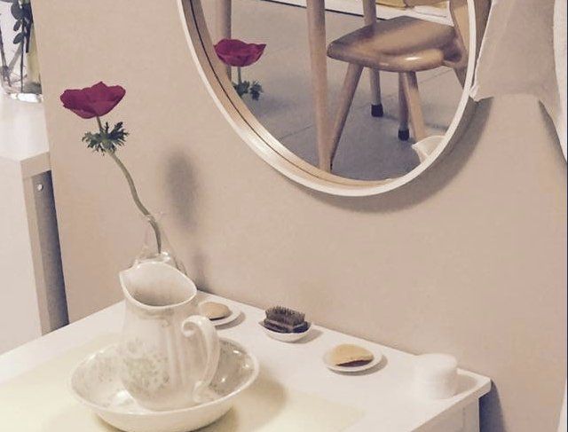 Lieux Petit meuble blanc avec tasse à thé, fleurs et miroir rond.