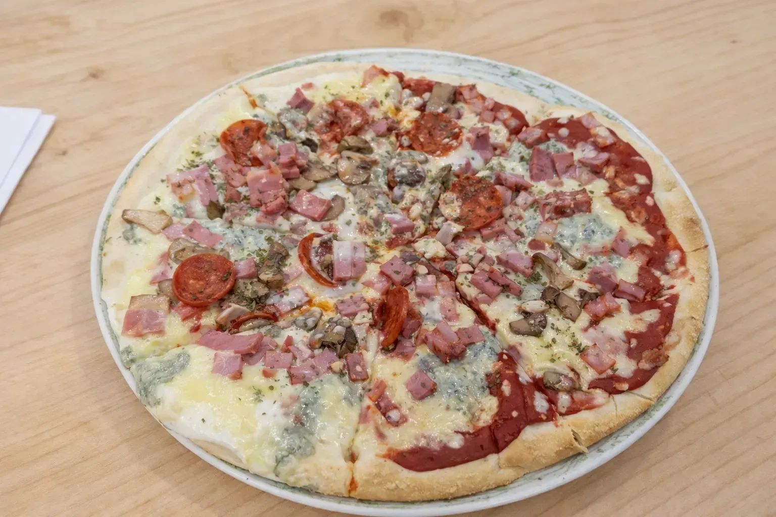 Pizza con ingredientes variados, dividida en porciones, en un plato de color claro.