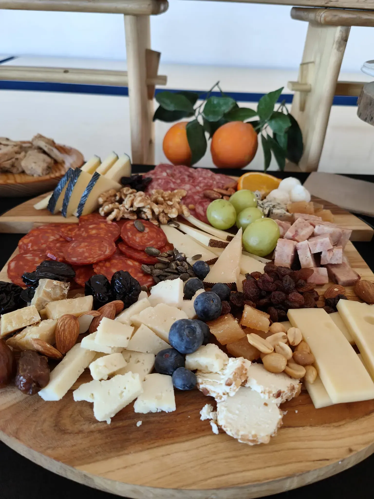 Tabla de embutidos de madera con quesos, carnes, frutos secos, frutas y verduras.