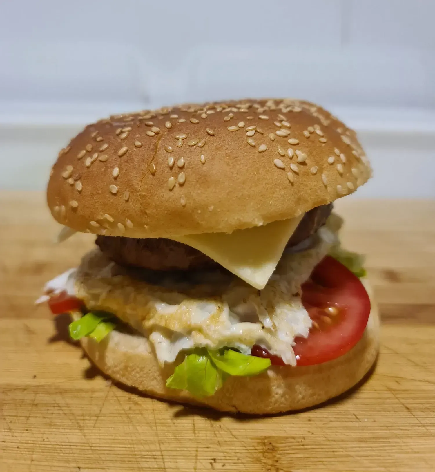 Hamburguesa en pan con semillas de sésamo, que contiene hamburguesa de carne, queso, tomate, huevo, lechuga y salsa.