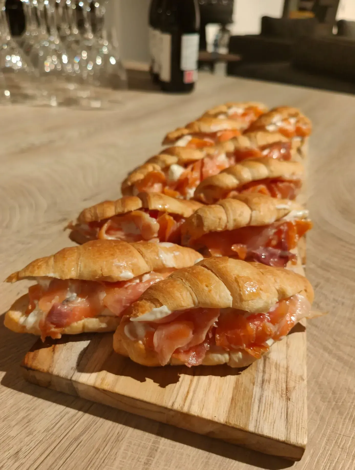 Sándwiches de croissant rellenos de salmón ahumado y queso crema sobre una tabla de madera.