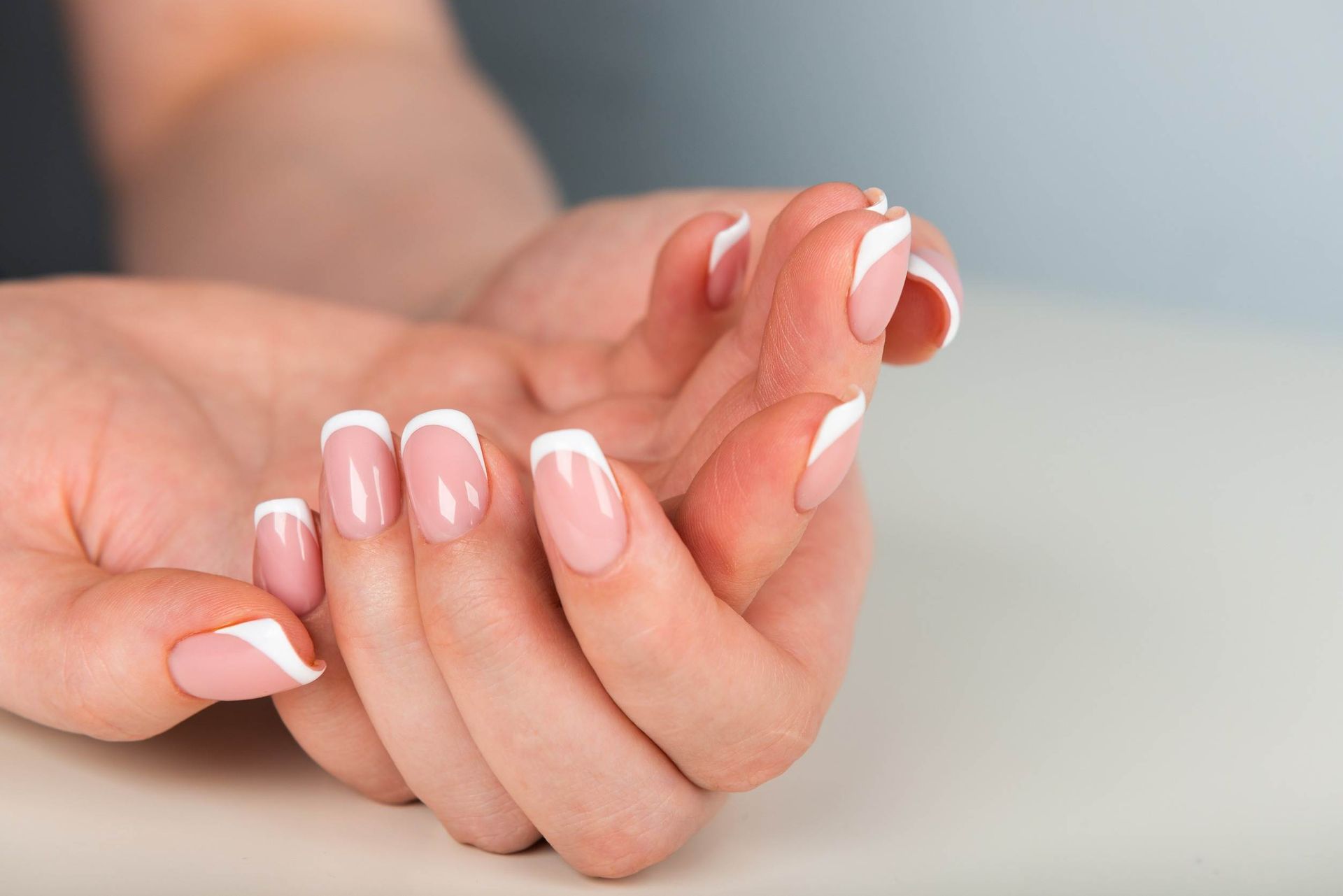 Un primer plano de las manos de una mujer con manicura francesa.