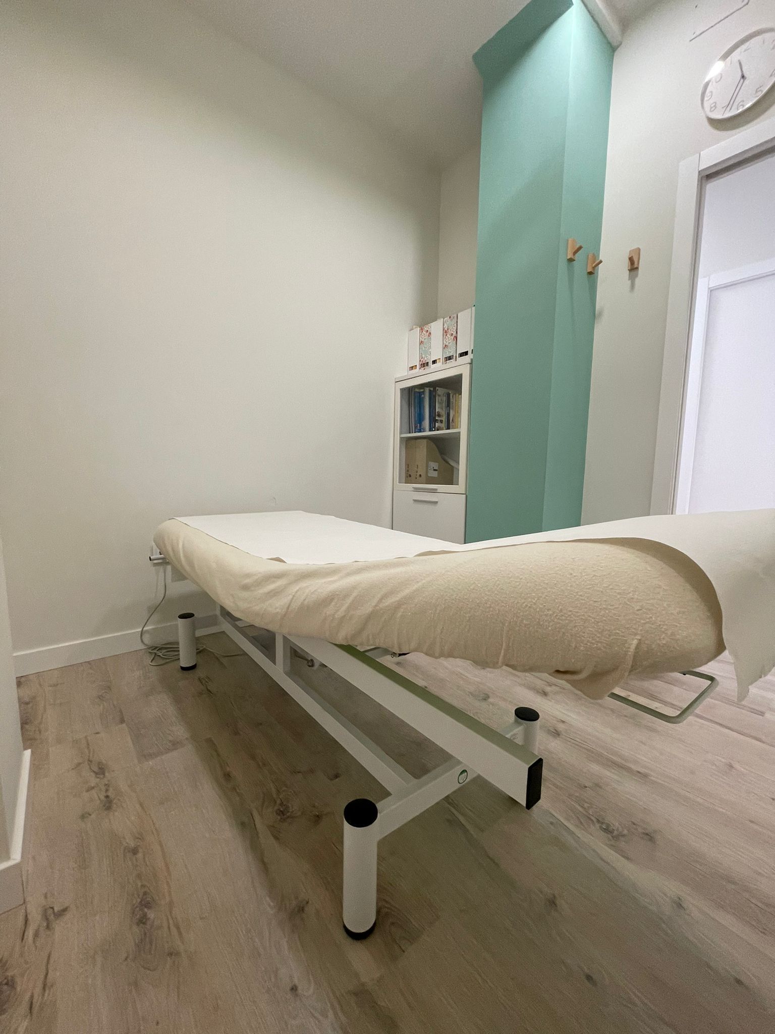 Una mesa de masajes en una habitación con un reloj en la pared.