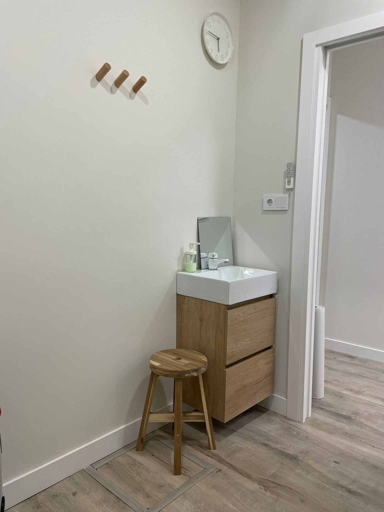 Un baño con lavabo, espejo y taburete.