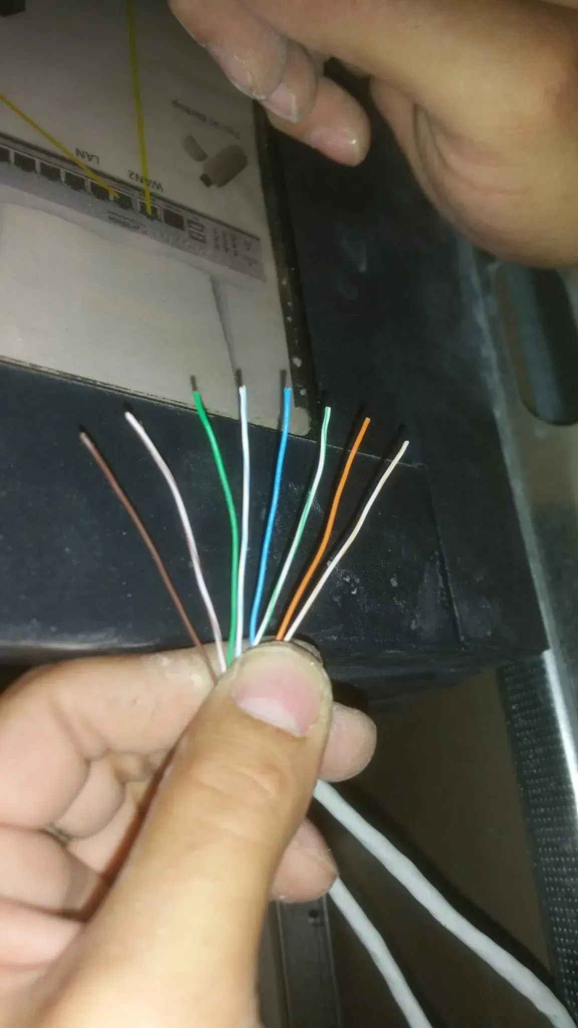 Manos que sostienen un manojo de cables multicolores sobre un fondo oscuro.