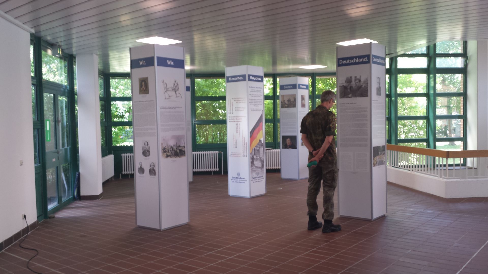 Soldat in Uniform, Ausstellung auf weißen Säulen in einem Raum mit Fenstern.