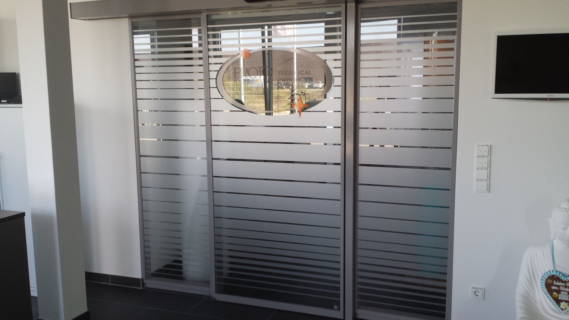 Automatische Glasschiebetüren mit horizontalen, mattierten Linien; Innenansicht.