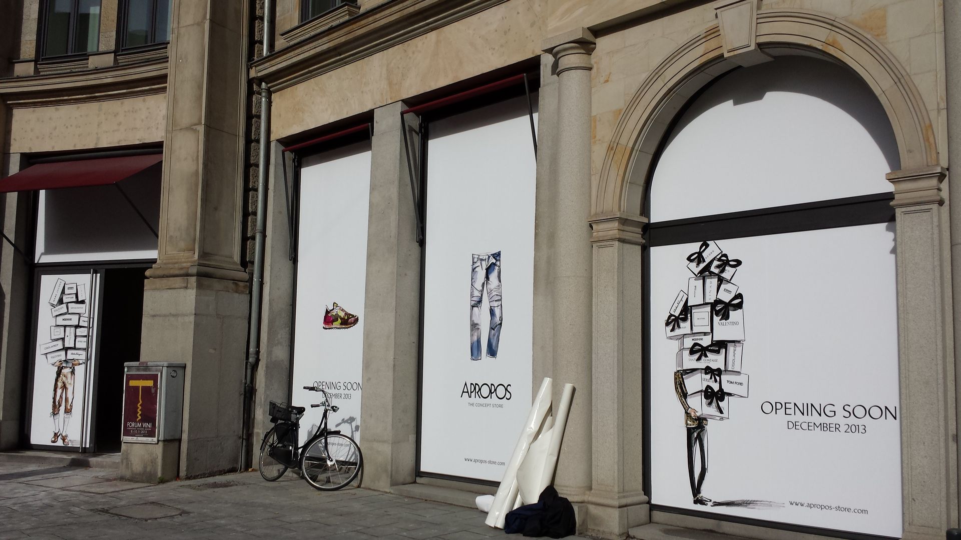 Geschlossenes Schaufenster mit Postern von Modeskizzen; Fahrrad auf dem Bürgersteig geparkt.