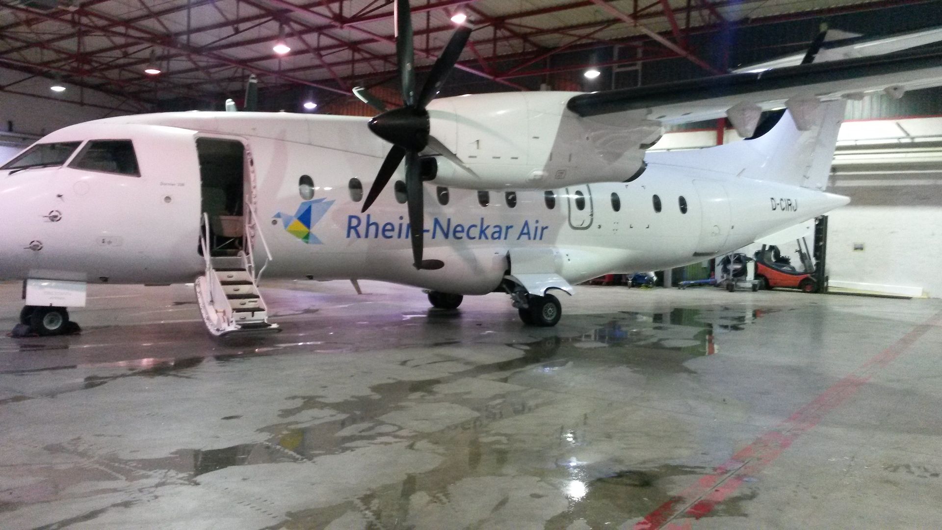 Turboprop-Flugzeug der White Rhein-Neckar Air in einem Hangar geparkt; Tür offen, Treppe ausgefahren.