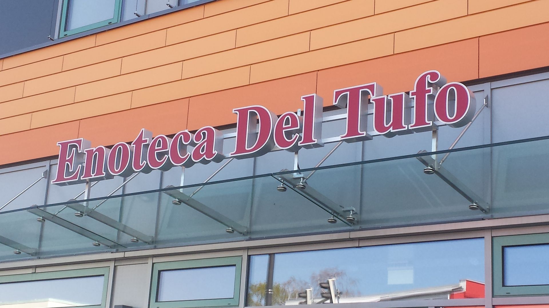 Leuchtbuchstaben „Enoteca Del Tufo“ an einer Gebäudefassade.