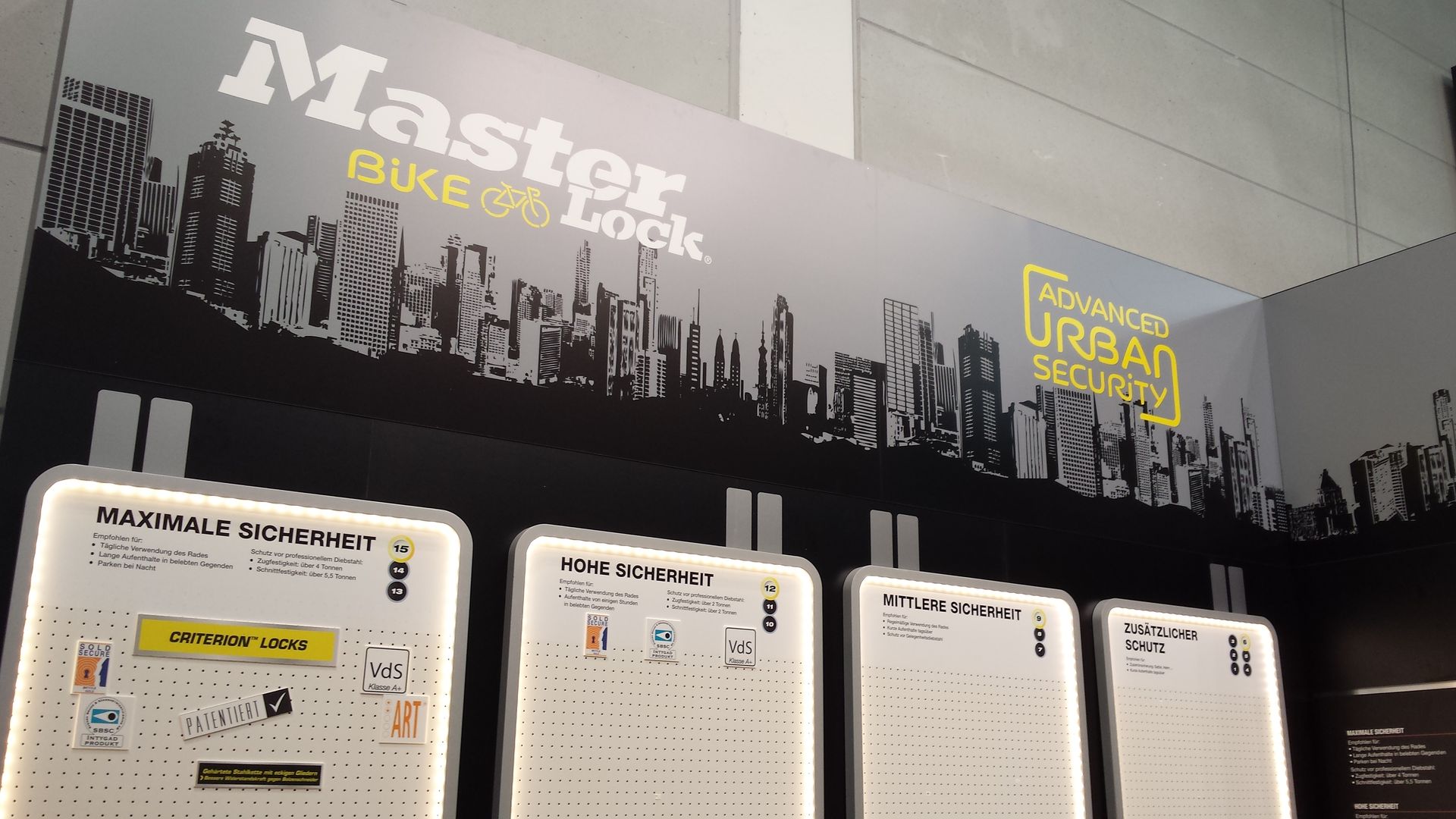 Display mit dem Master Bike Lock-Logo und Postern mit Details, urbaner Hintergrund.