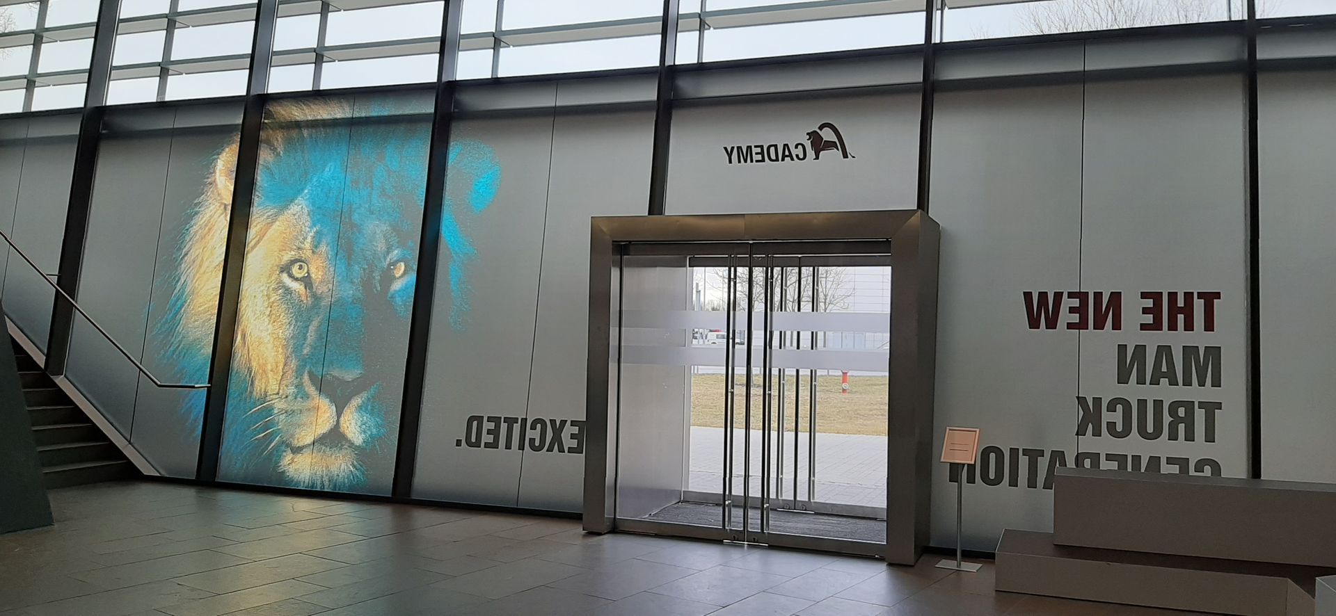 Ein Gebäudeeingang mit einer Löwengrafik und dem Text „Die neue MAN-Lkw-Generation“.