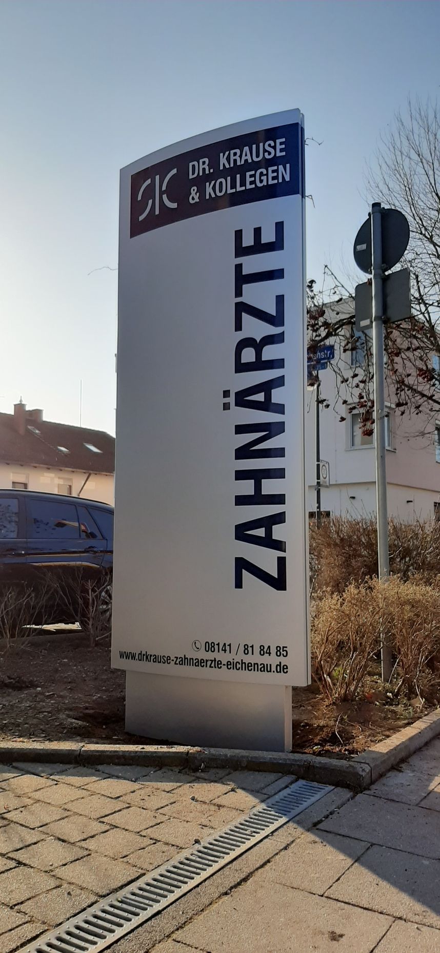 Schild einer Zahnarztpraxis, „Zahnärzte“, auf Deutsch, mit Adresse und Logo.