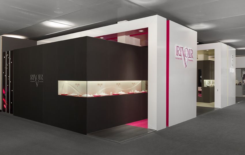 Schmuckladen-Ausstellung mit schwarz-weißen Wänden, rosa Akzenten und beleuchteten Schmuckvitrinen.