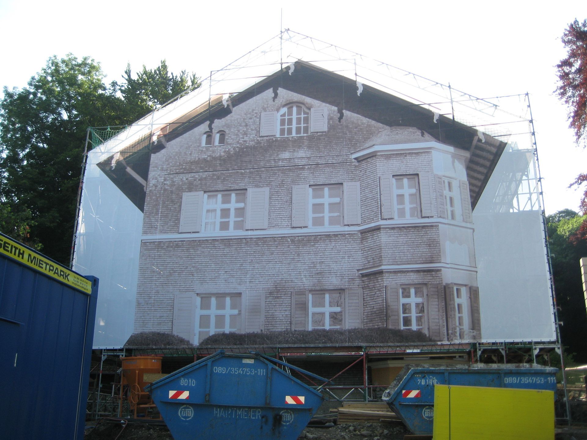 Gebäudefassade mit Gerüst und aufgedrucktem Bild bedeckt, wahrscheinlich während der Renovierung.