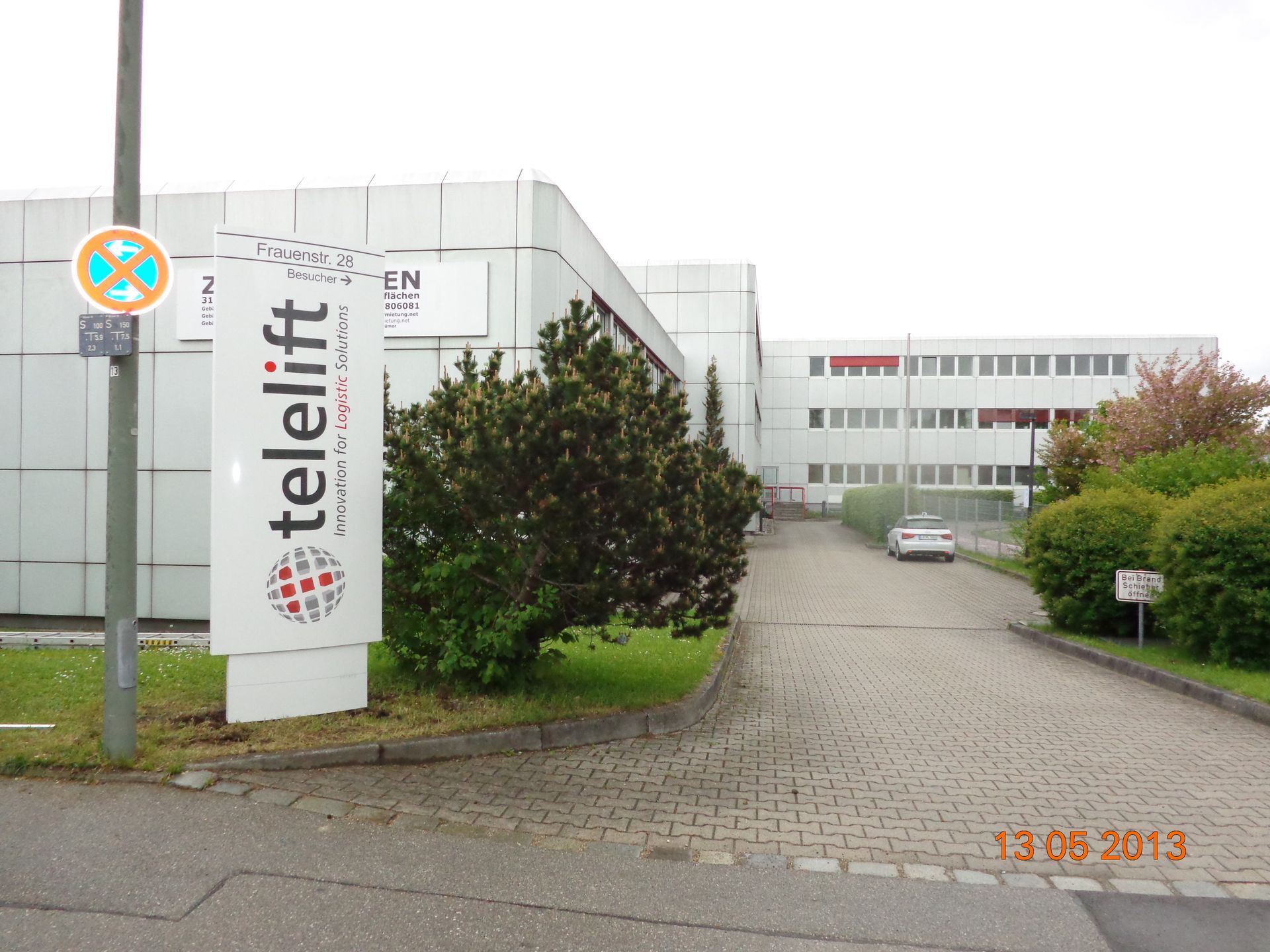 Schild für Telelift, Gebäude im Hintergrund, Auffahrt, bewölkter Tag.