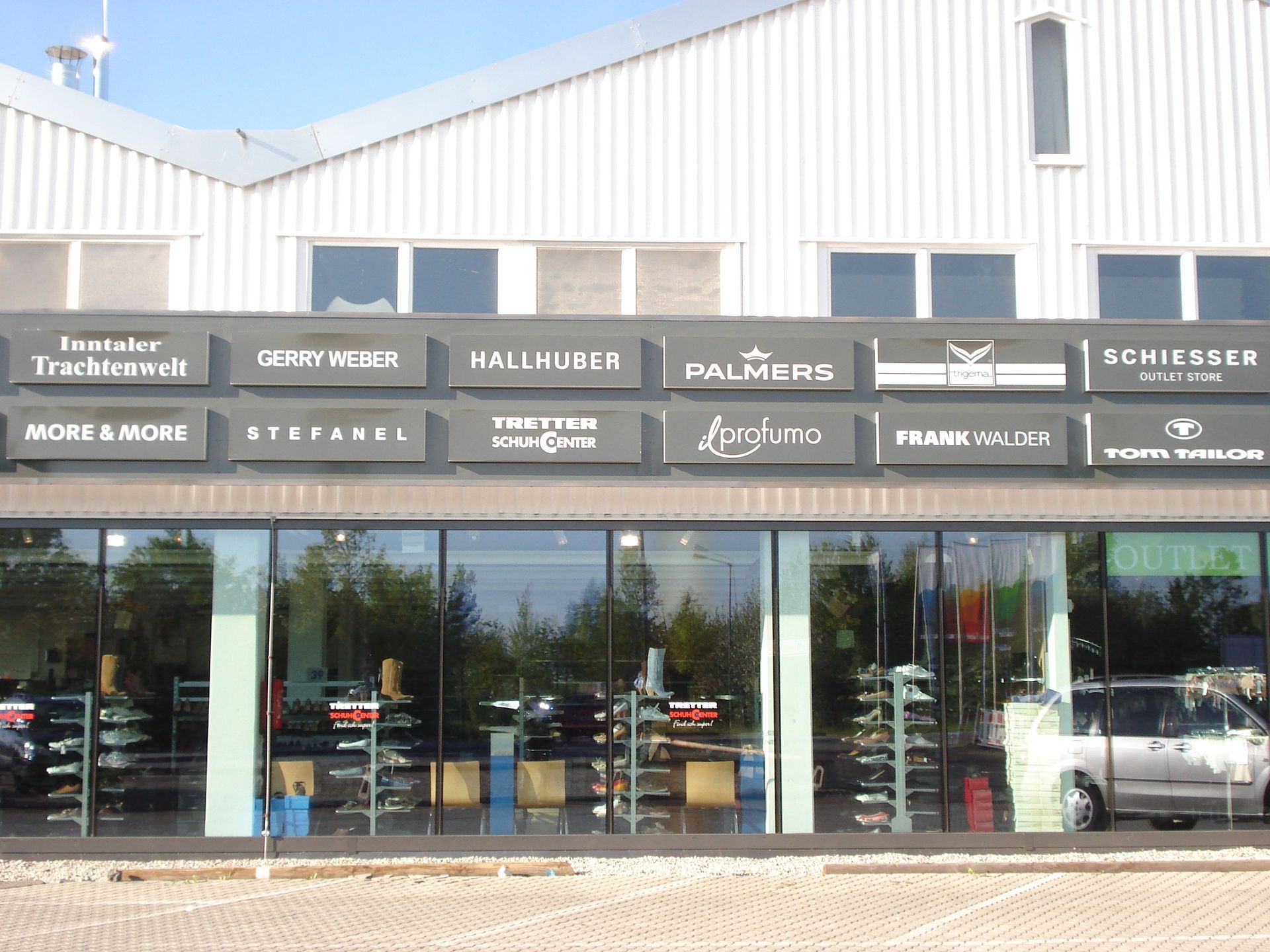 Mehrere Leuchtkästen verschiedener Firmen über Glasfenstern.