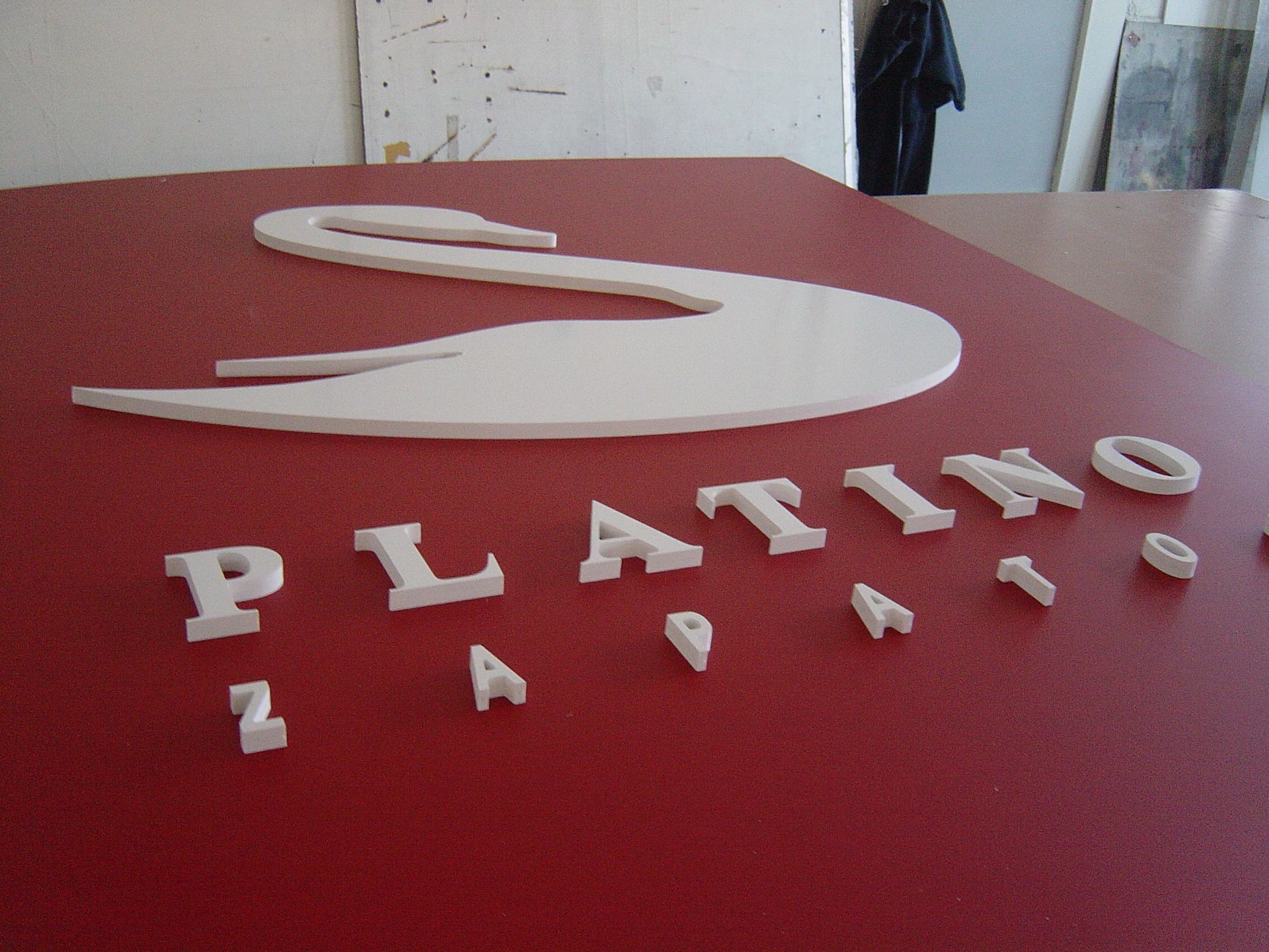 Rotes Schild mit einem weißen Schwanensymbol und dem Wort „PLATINO“ in weißen Buchstaben.