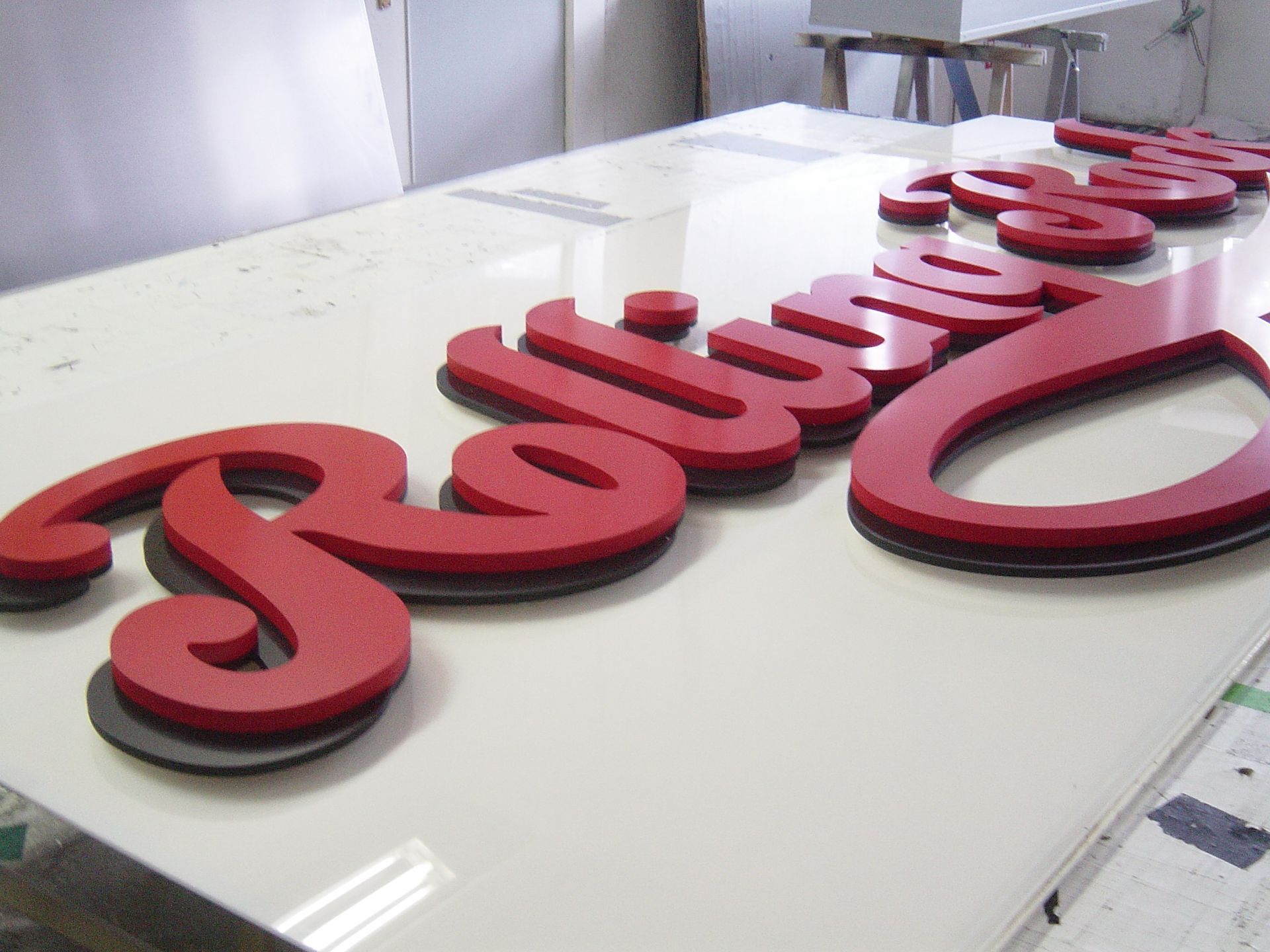 Auf einer weißen Oberfläche werden rote und schwarze „Rolling“-Schildbuchstaben hergestellt.