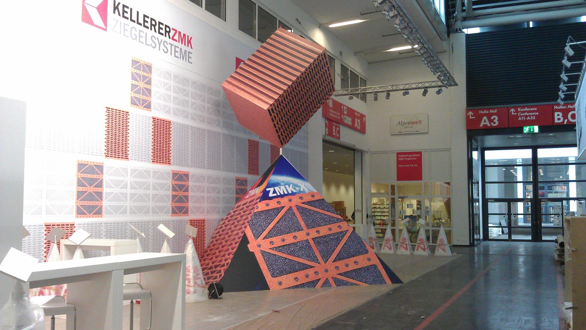 Ein Messestand mit einer großen kartenhausähnlichen Struktur in einer Ausstellungshalle.
