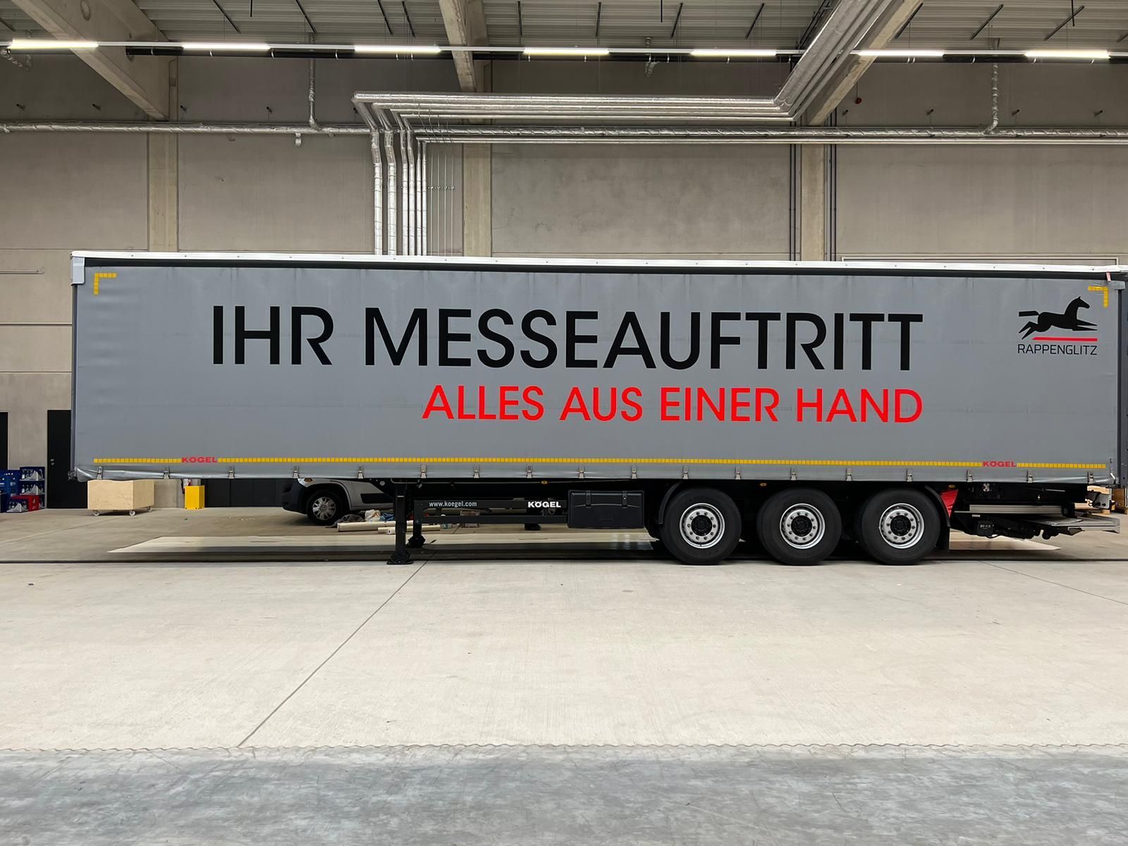 Grauer Anhänger mit deutschem Werbetext „Ihr Messeauftritt“.