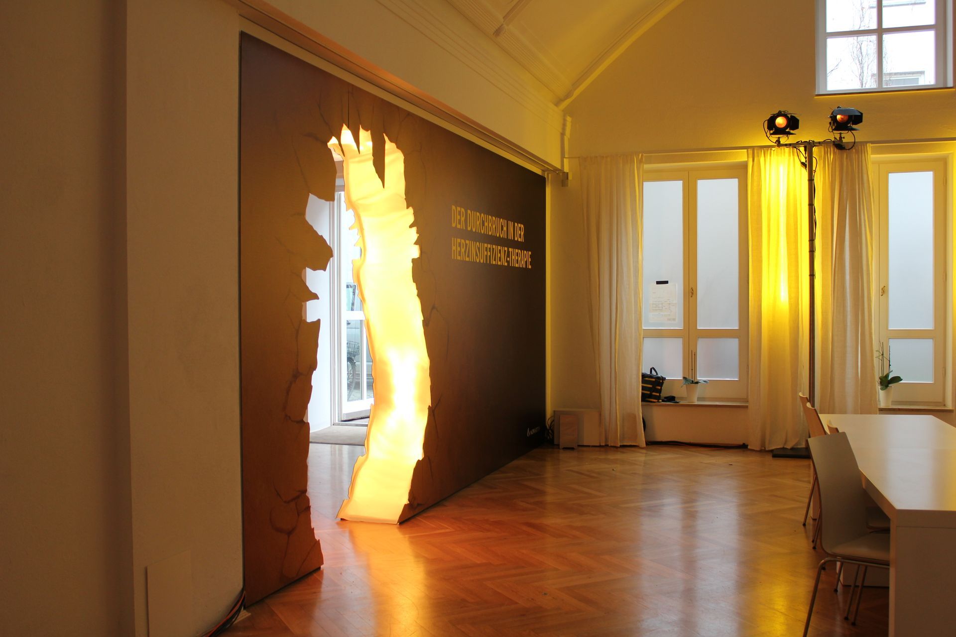 Ein Raum mit einem von hinten beleuchteten Ausschnitt, gelben Lichtern und einem weißen Tisch.