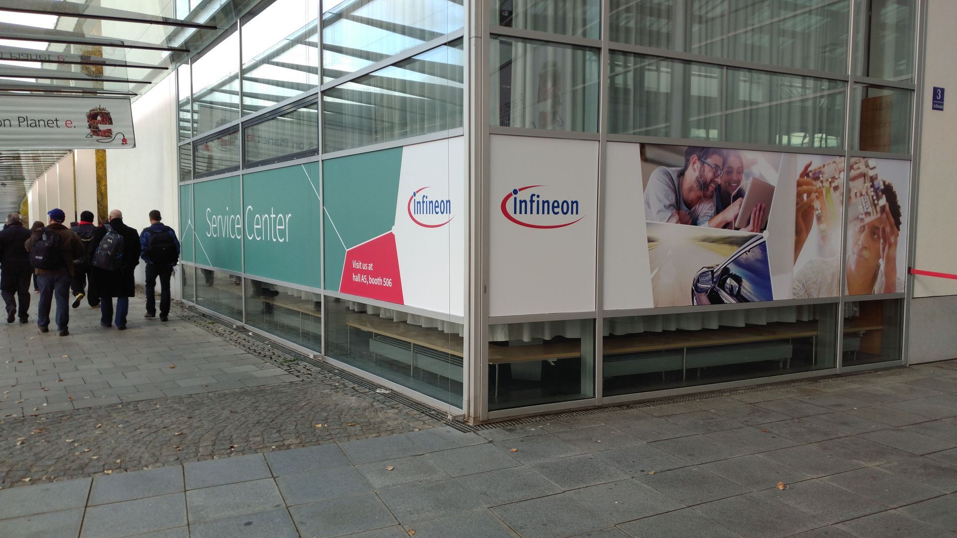 Menschen gehen an einem Gebäude mit Infineon-Werbung vorbei.