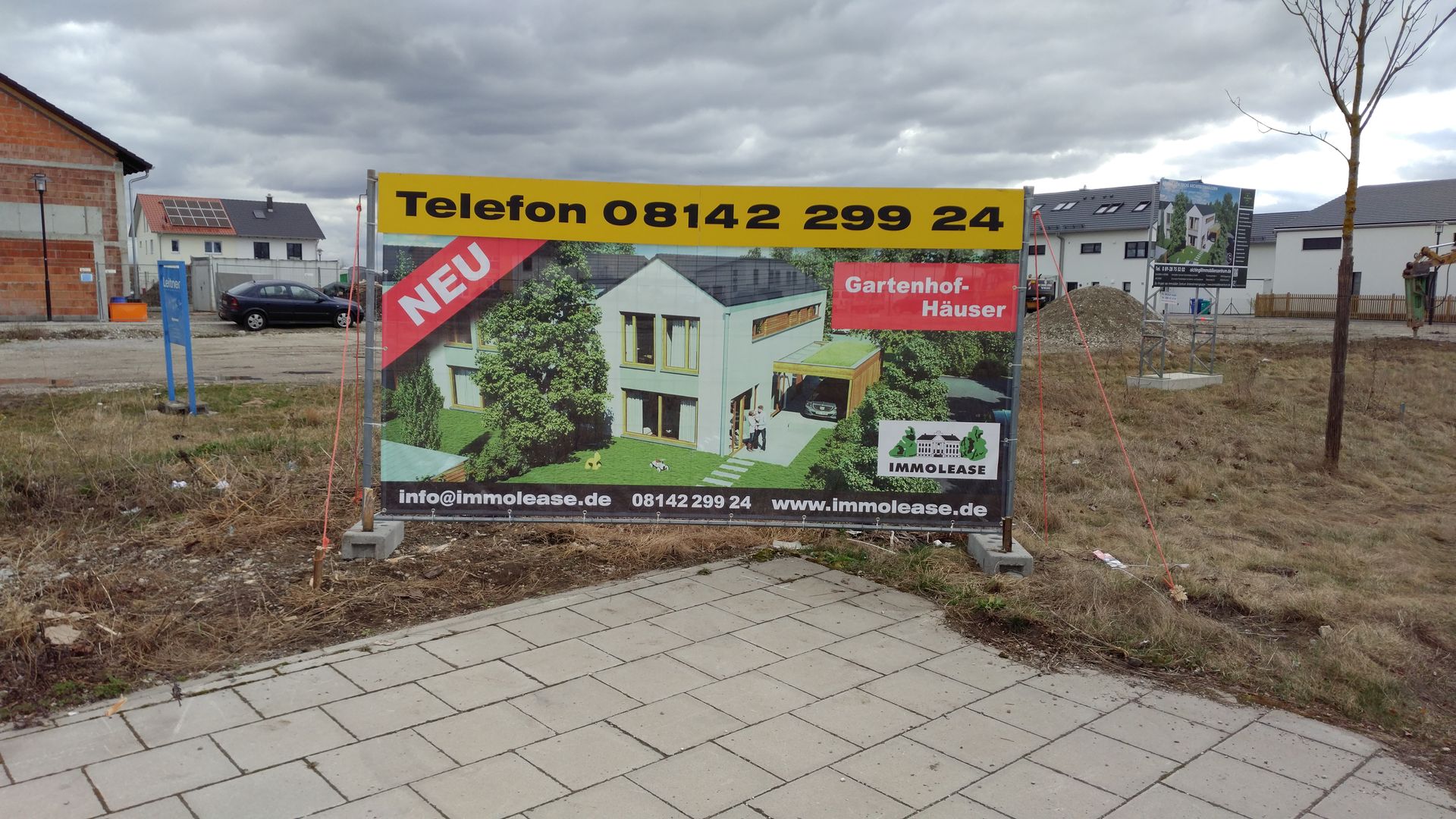 Immobilienschild: moderne Hausillustration, „NEU“-Aufkleber, Telefonnummer, Vorstadt-Motiv.