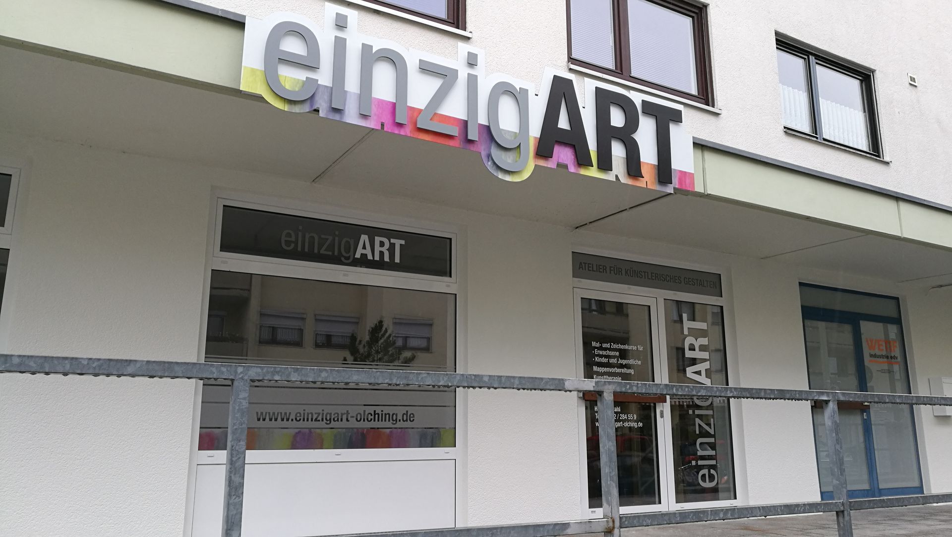 „EinzigART“-Ladenfront mit buntem Schild.