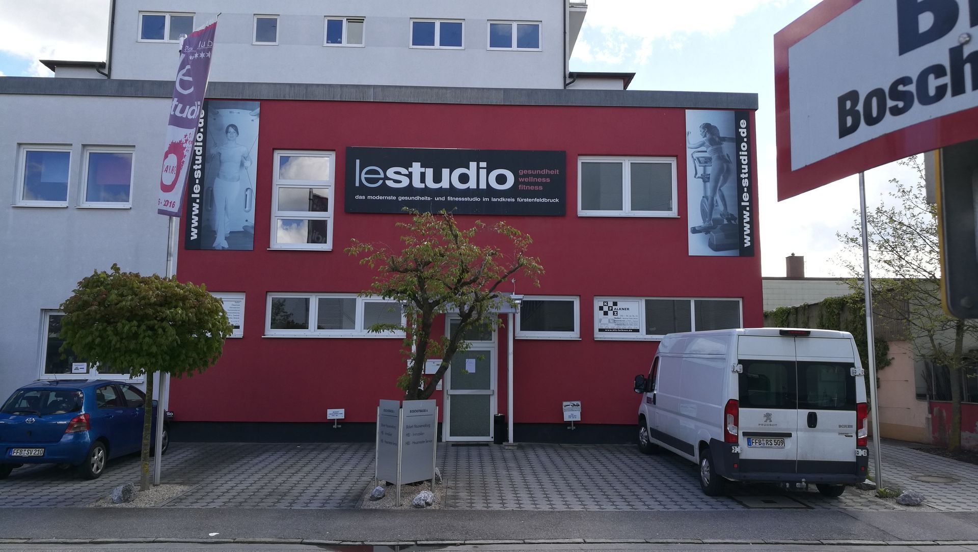 Rotes lcstudio-Gebäude mit einem davor geparkten weißen Lieferwagen.