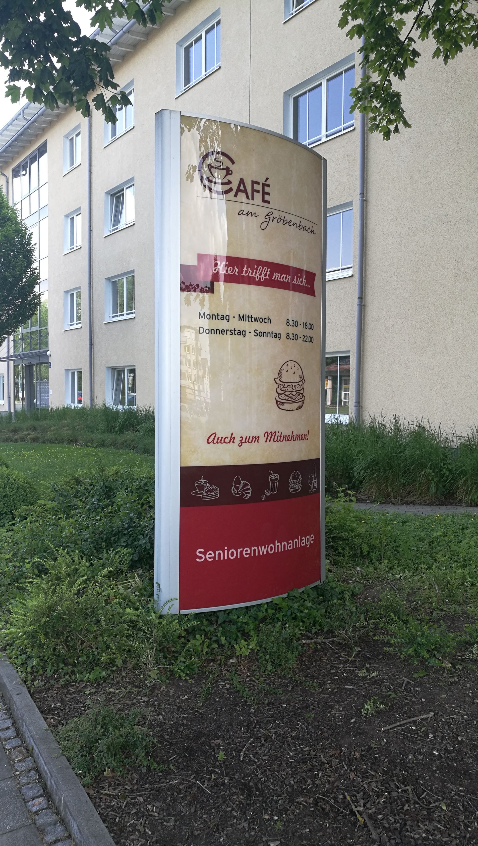 Werbepylon für ein Café vor einem Gebäude.