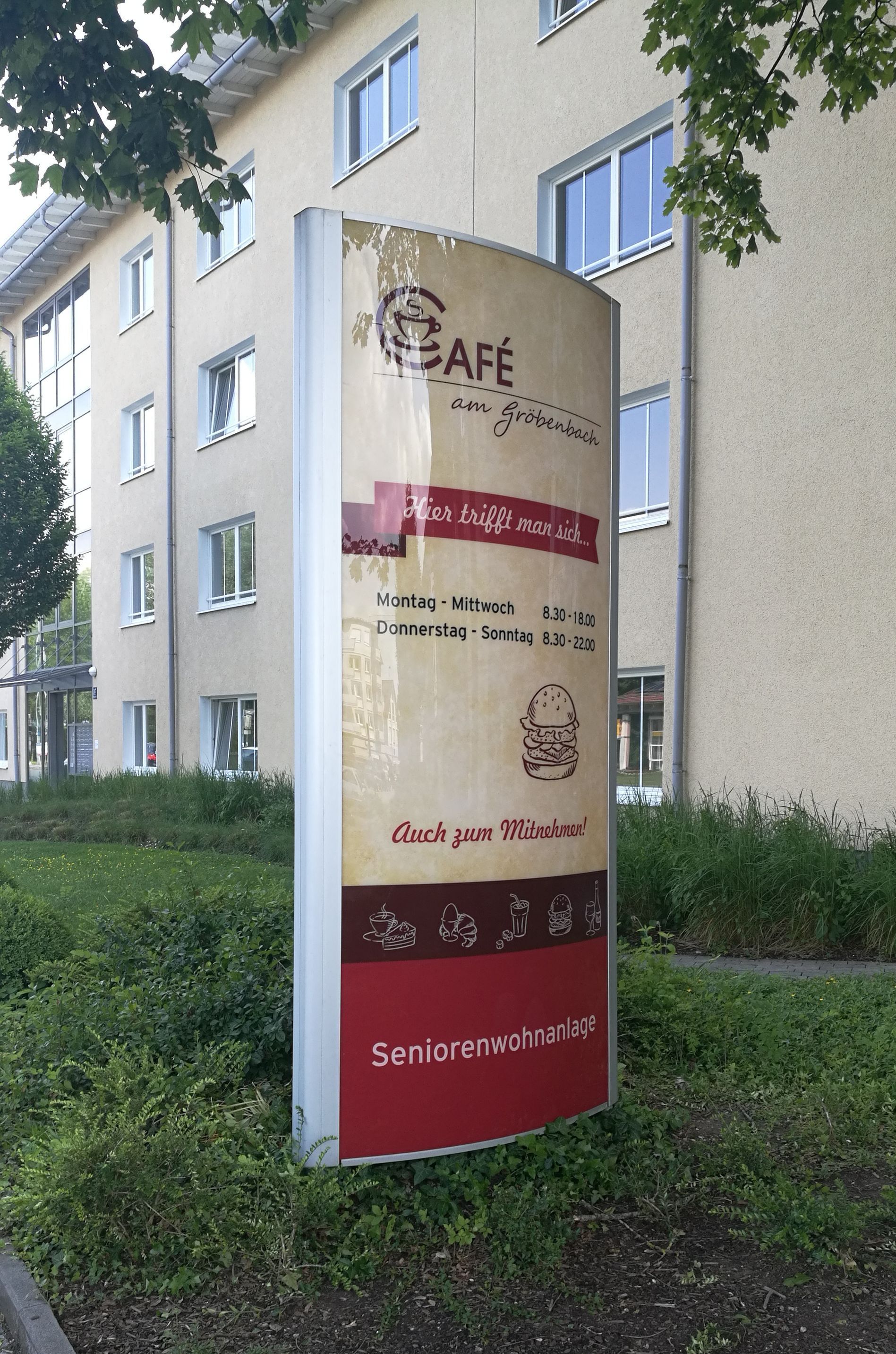 Werbepylon für ein Café vor einem Gebäude.