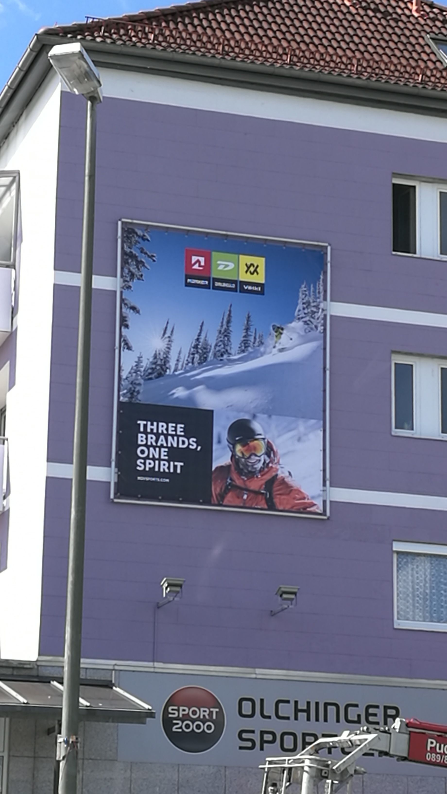 Werbetafel im XXL-Format an einem violetten Gebäude.