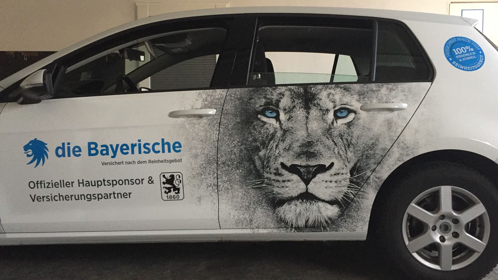 Weißes Auto mit Löwengrafik und „die Bayerische“-Logo.