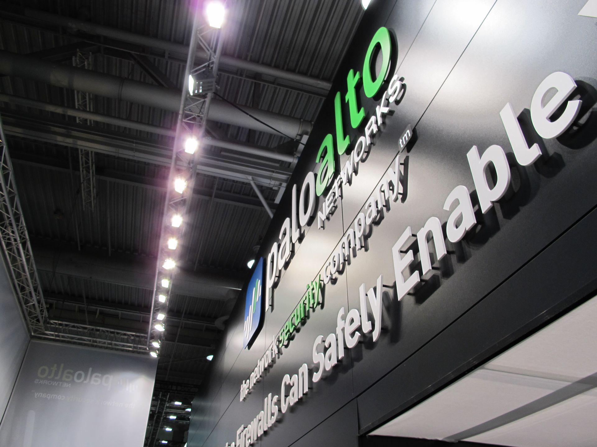 Schild für Palo Alto Networks an einer schwarzen Wand, grünes Logo, weißer Text, unter hellem Licht.
