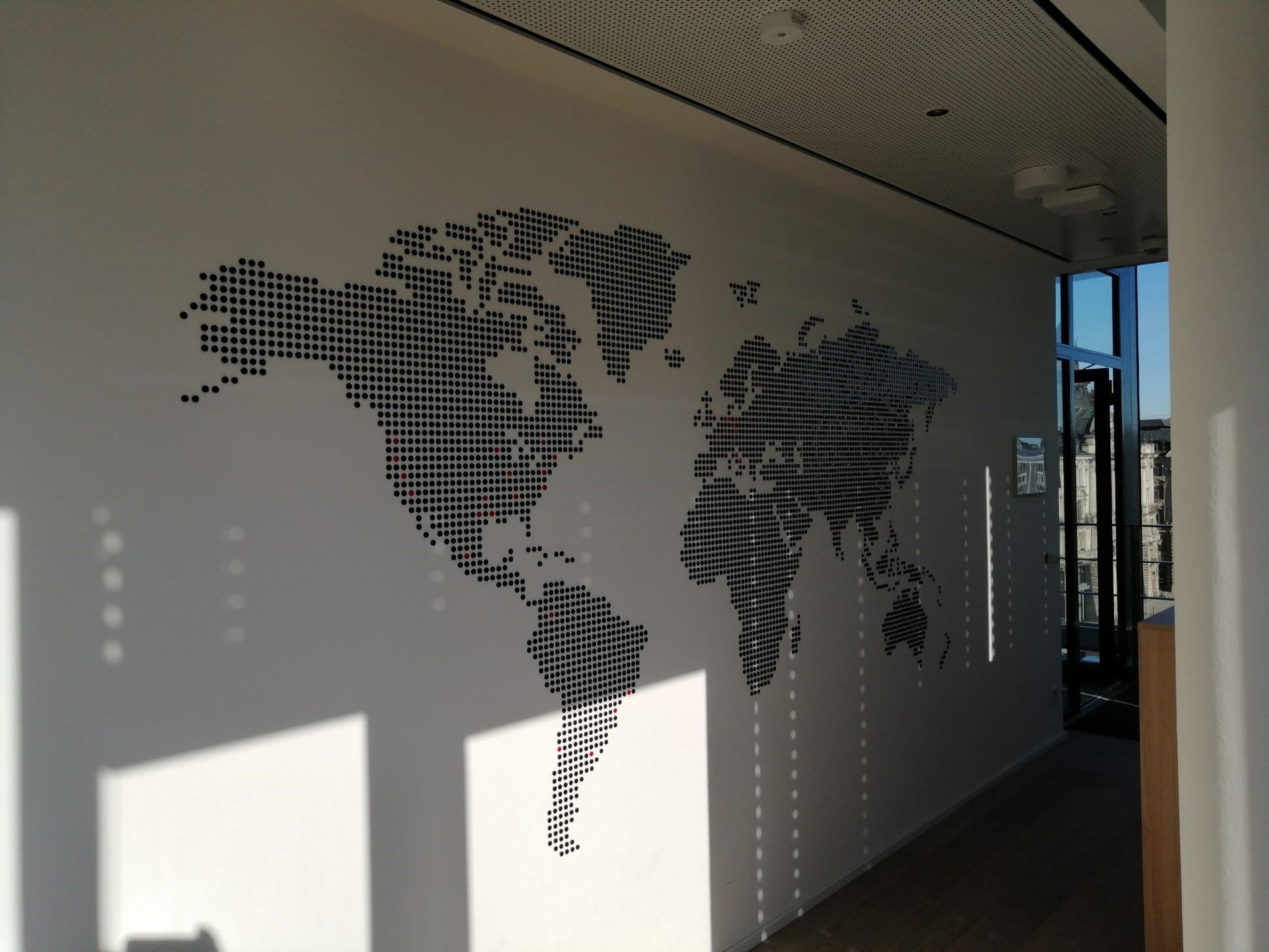 Weltkartengrafik auf weißer Wand mit Schatten.