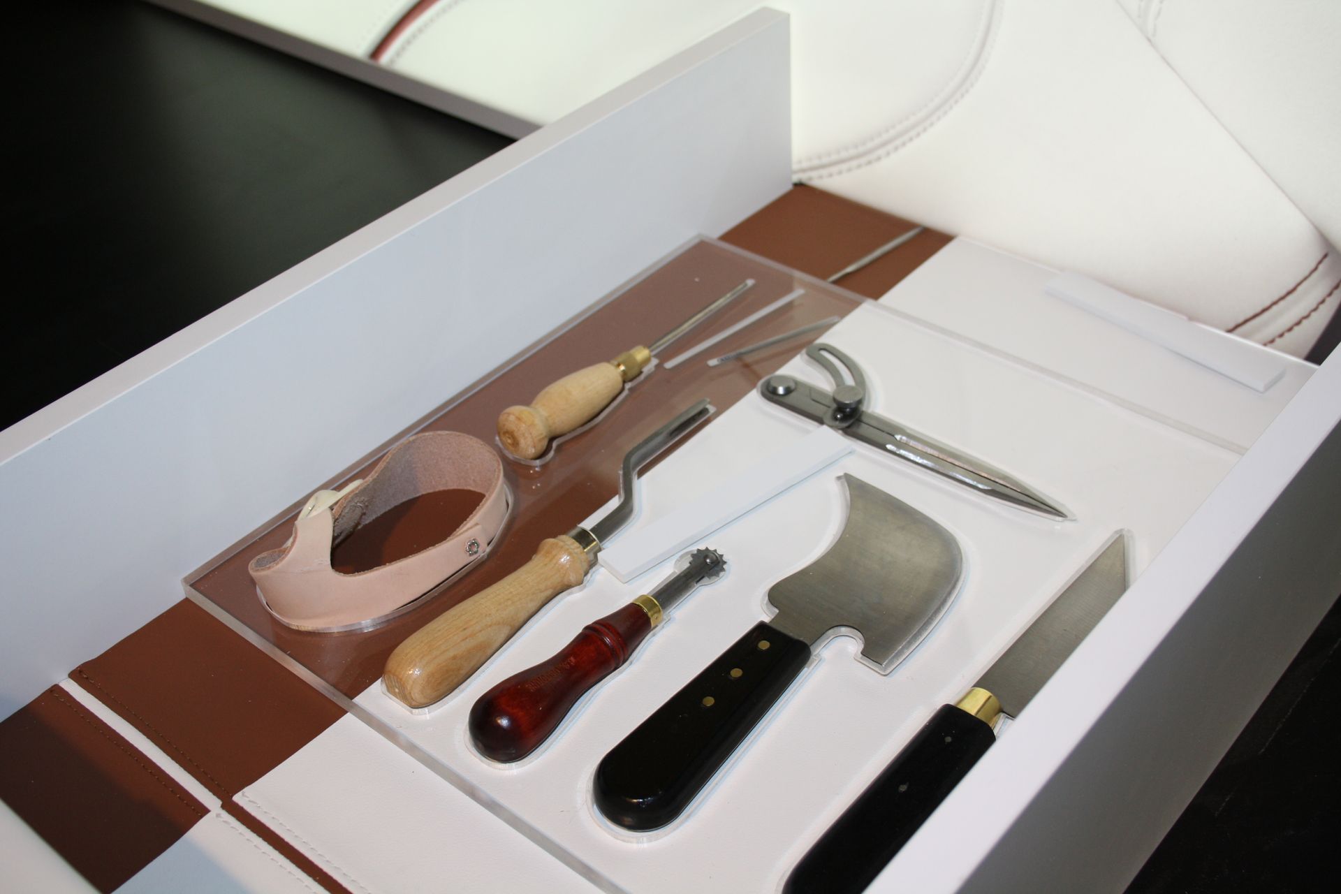 Auf einem Tablett angeordnete Werkzeuge; darunter Messer, ein Lederschneidewerkzeug und kleine Gabeln.