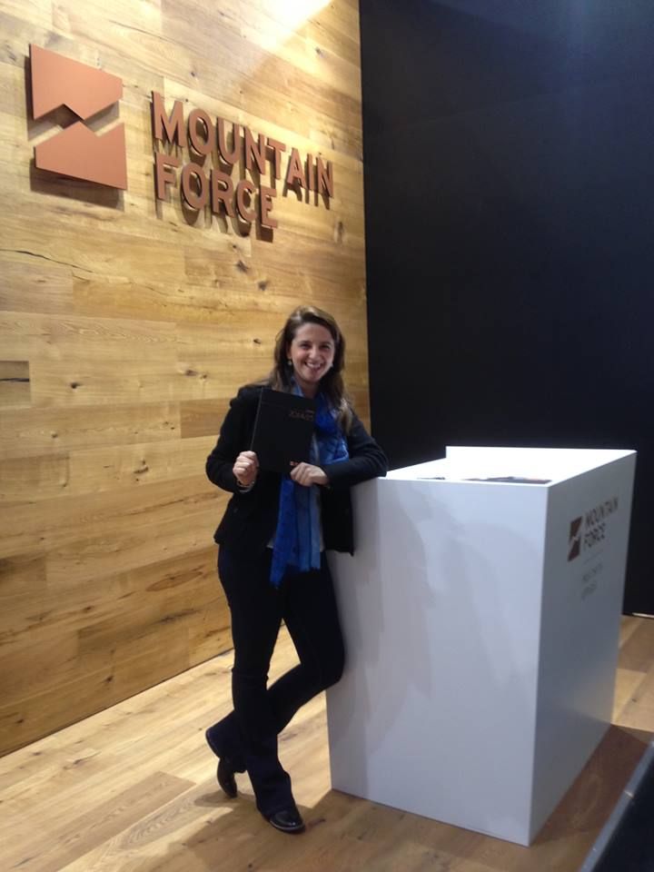 Frau steht in der Nähe eines Standes mit dem „MOUNTAIN FORCE“-Logo. Sie trägt Schwarz und einen blauen Schal.