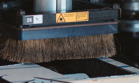 Eine Maschine schneidet ein Stück Metall mit einem Muster darauf.