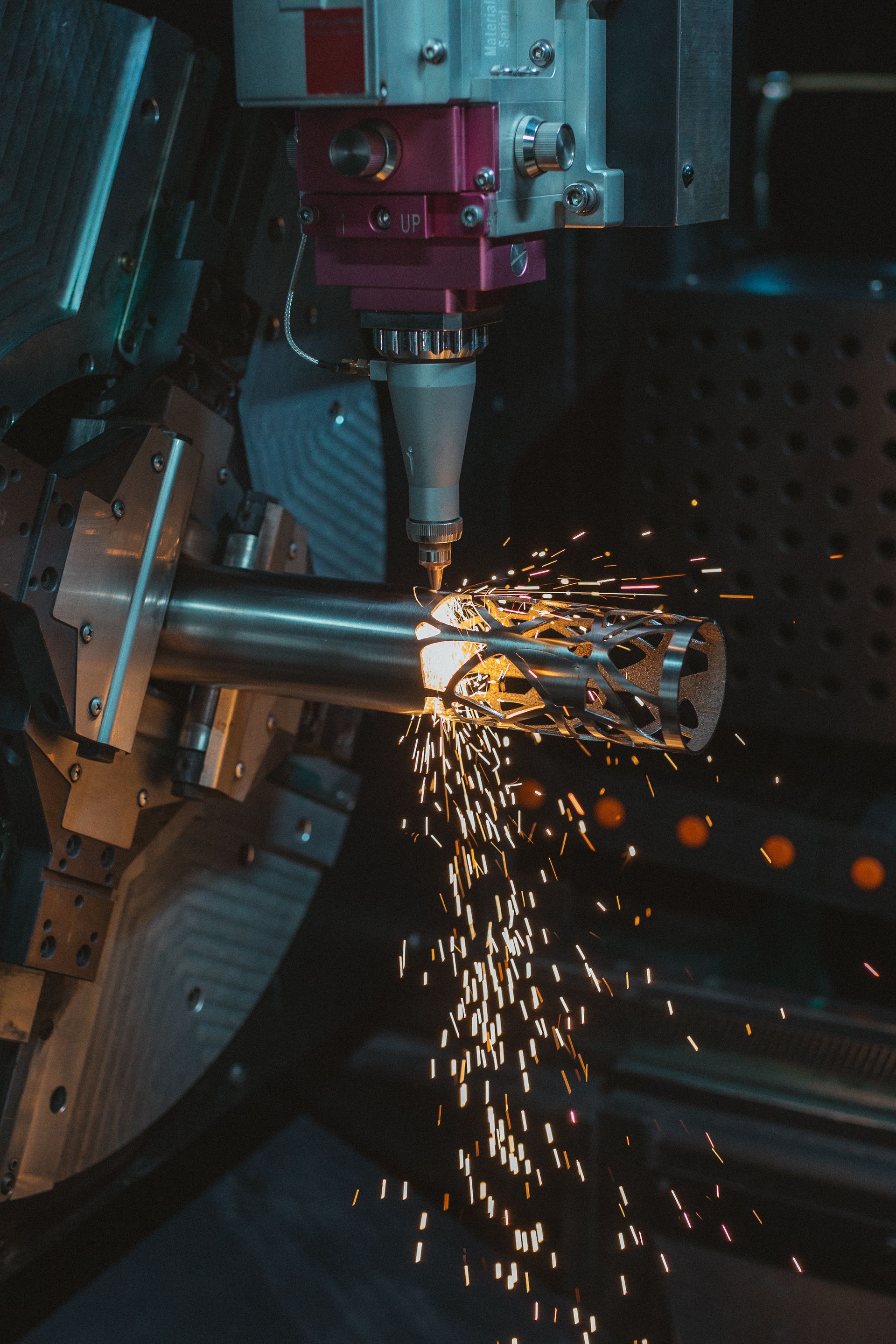 Eine Maschine schneidet ein Stück Metall, wobei Funken entstehen.