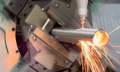 Eine Maschine schneidet ein Metallrohr, wobei Funken austreten.
