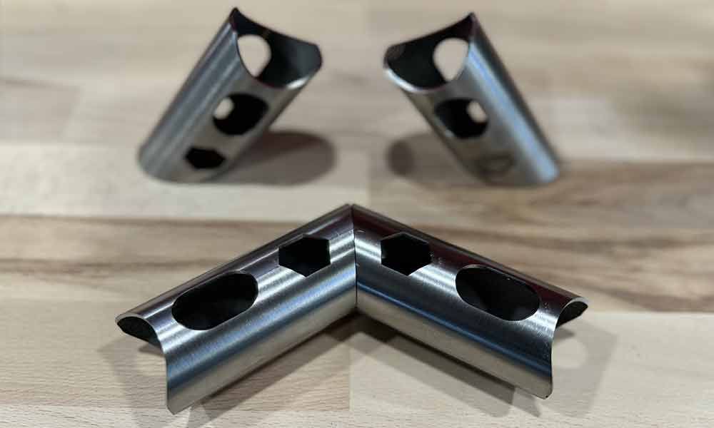 Drei Metallrohre liegen auf einem Holztisch.