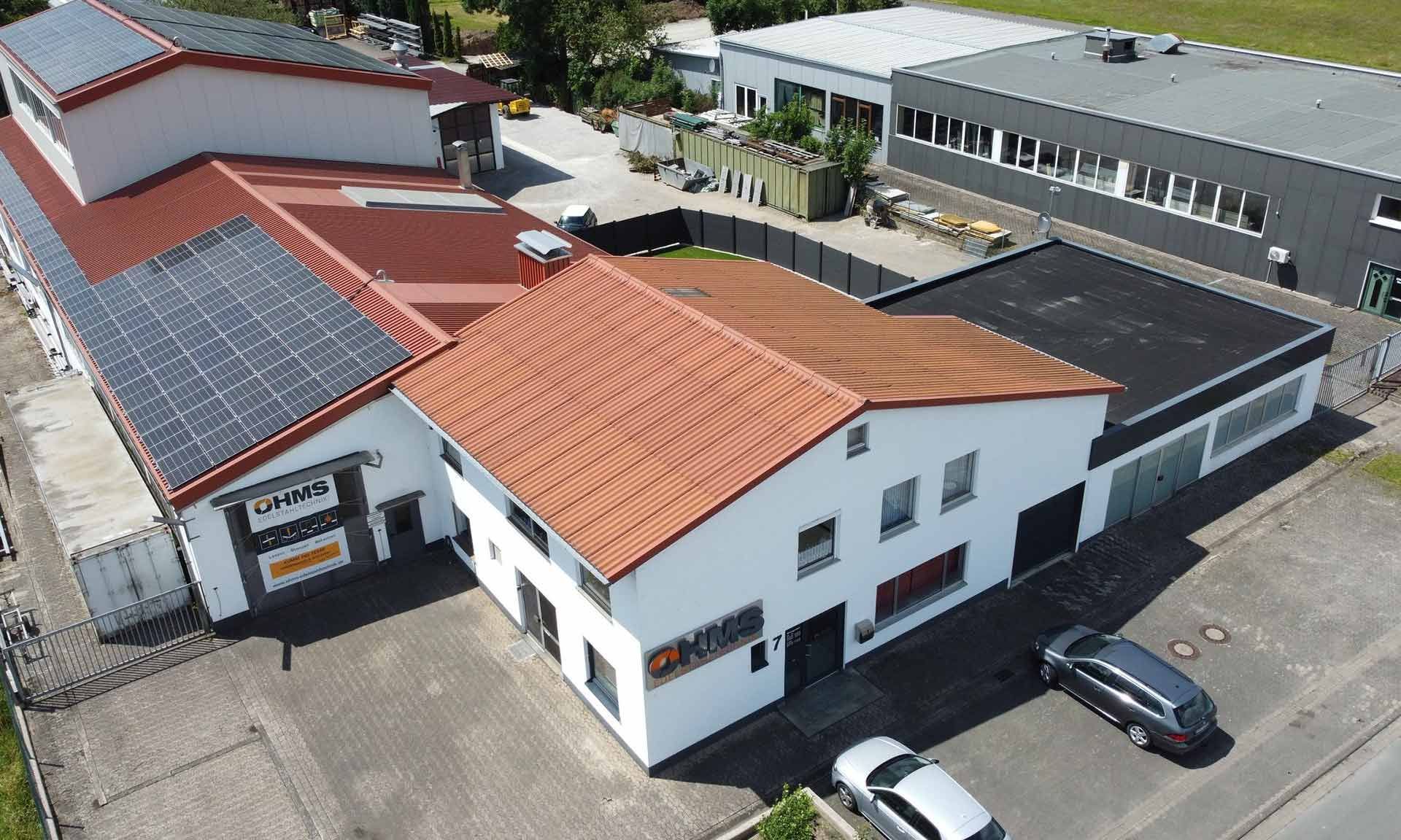 Eine Luftaufnahme eines großen Gebäudes mit Solarmodulen auf dem Dach.
