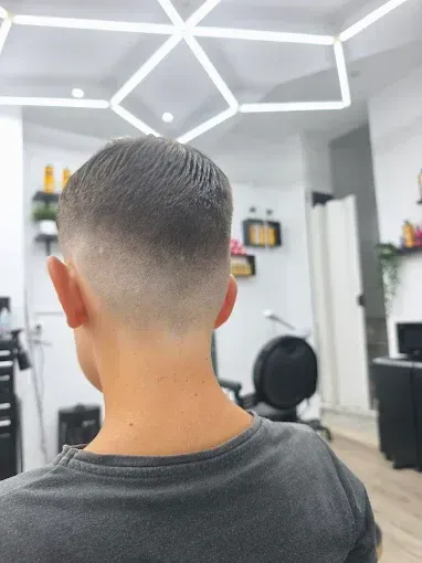 Persona con un corte de pelo cónico, de pie en un salón muy iluminado.