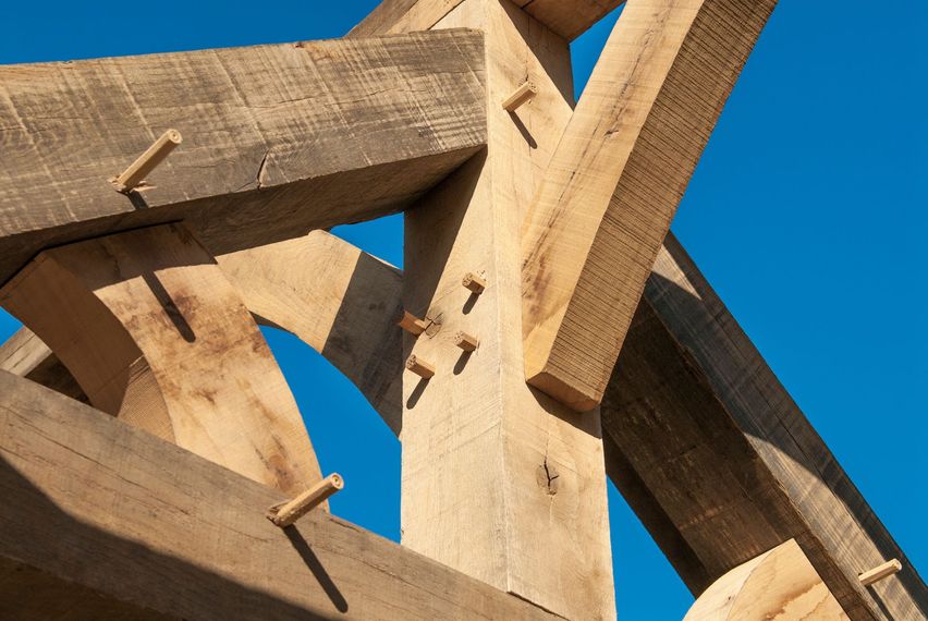 Gros plan sur des poutres en bois entrecroisées se détachant sur un ciel bleu clair.