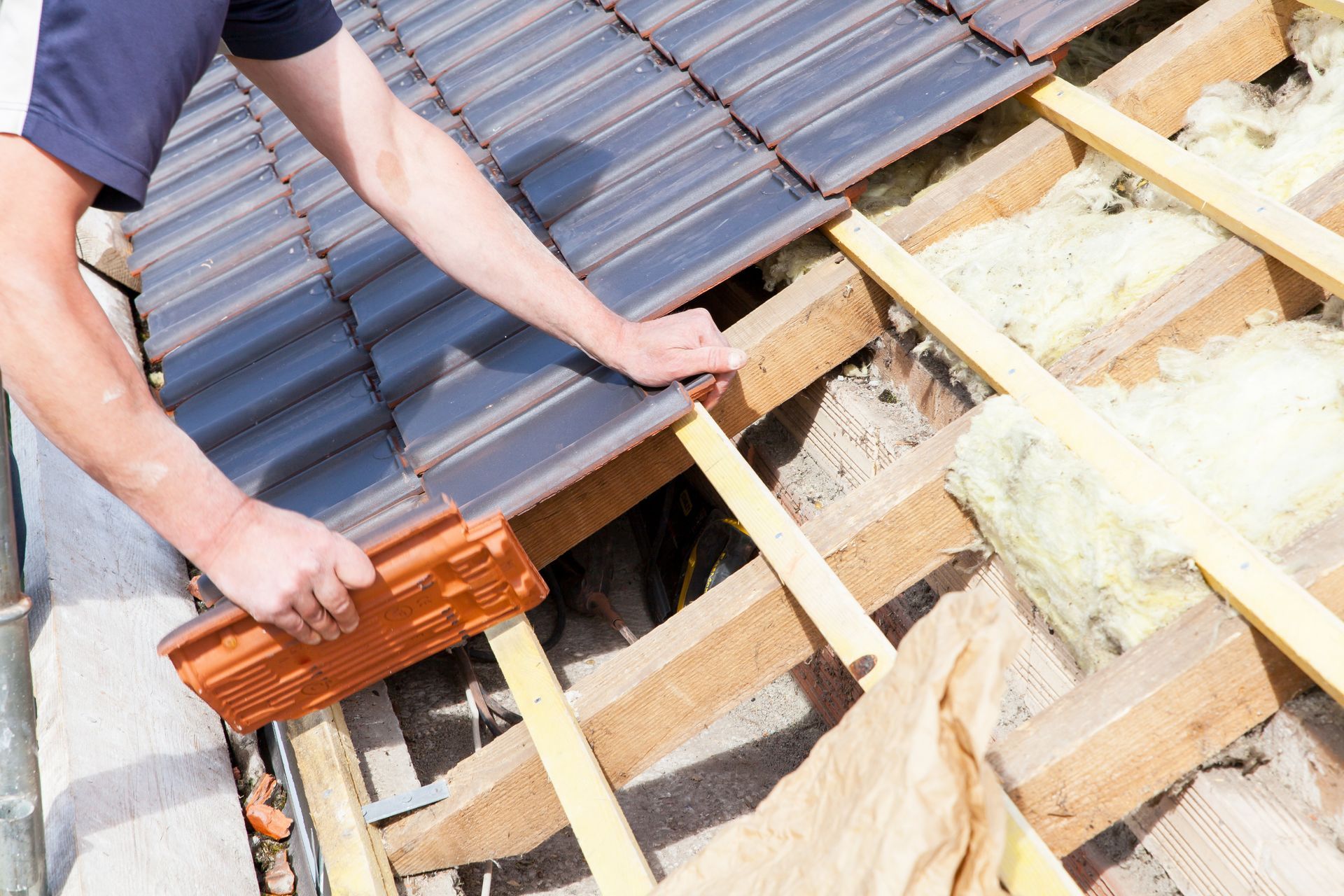 Ouvrier installant des tuiles rouges sur un toit en construction